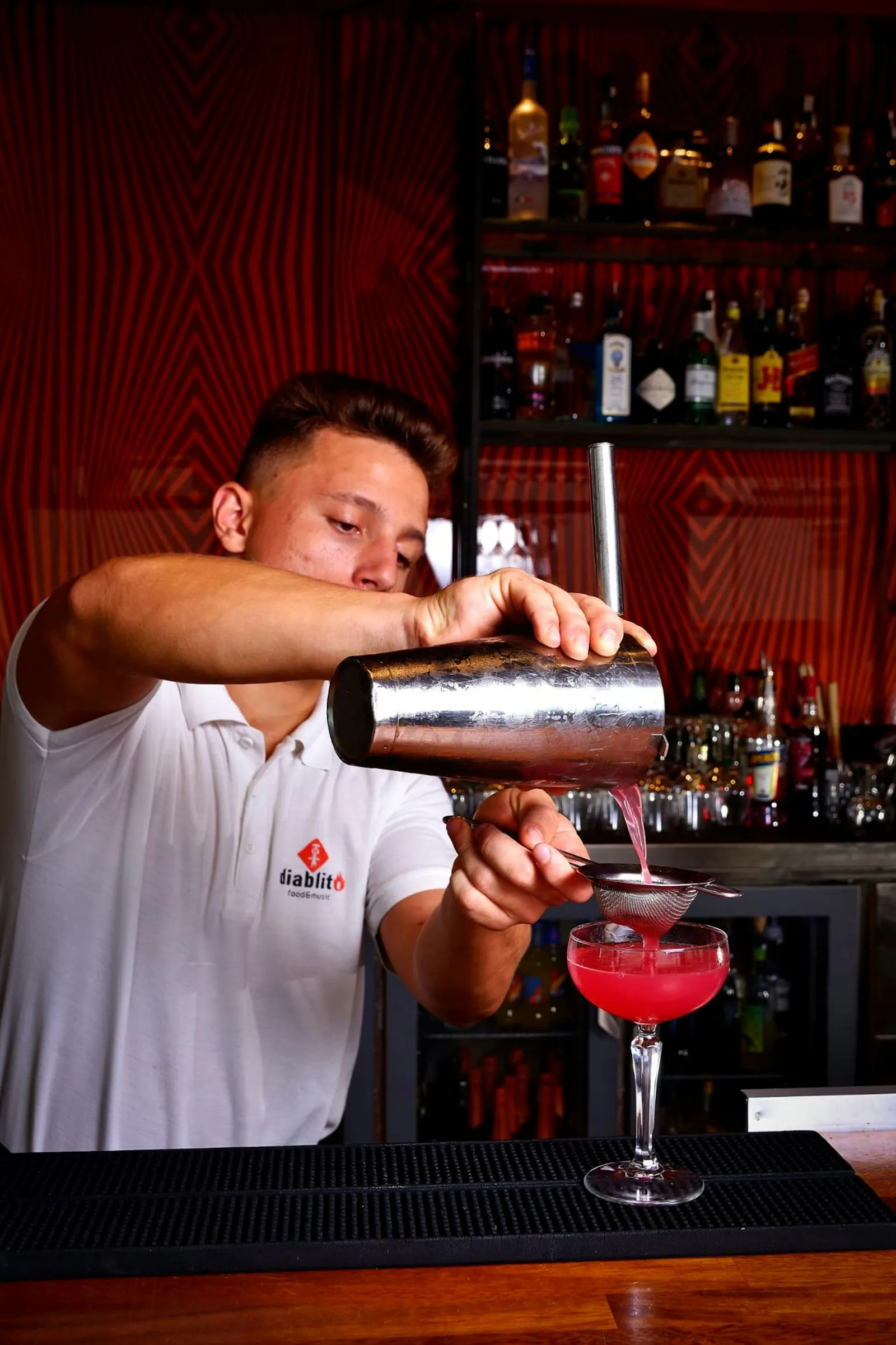A bartender finishing a cocktail at the bar