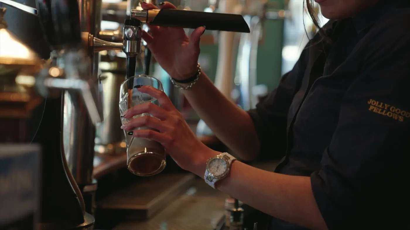 A Jolly Good Fellows team member pouring a beer behind the bar
